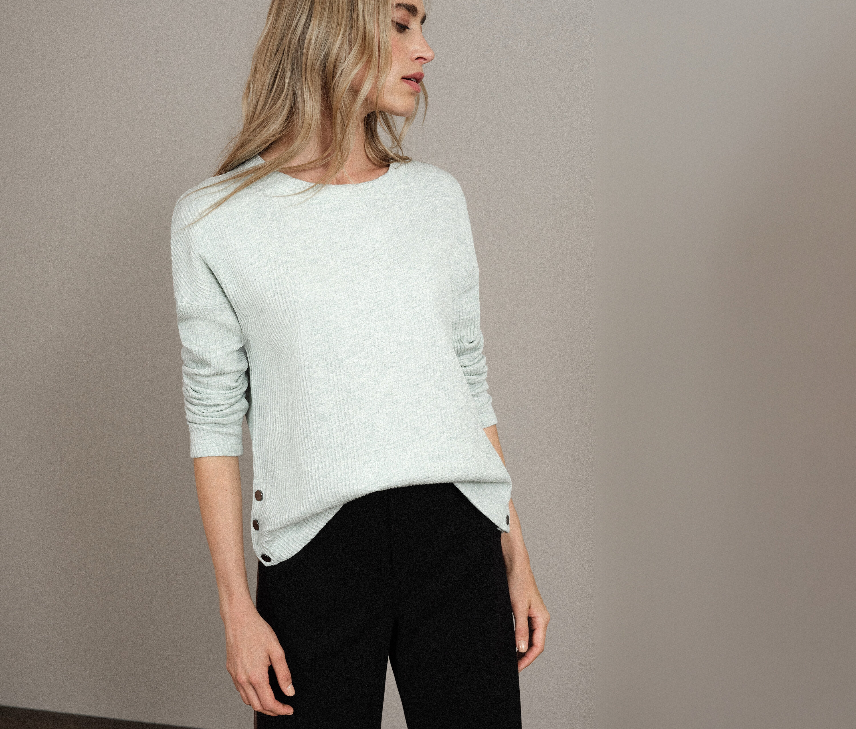 Frau trägt ein hellblaues Street One Shirt mit Struktur und eine schwarze Hose.