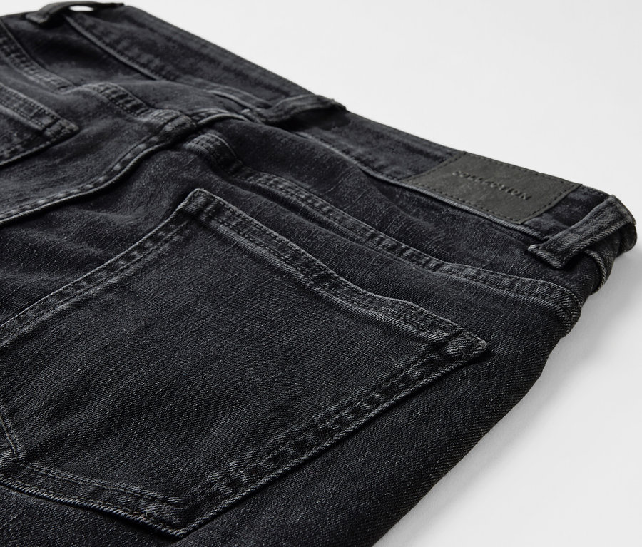 Detailaufnahme einer schwarzen Jeans mit Taschen und einem Lederpatch auf der Rückseite.