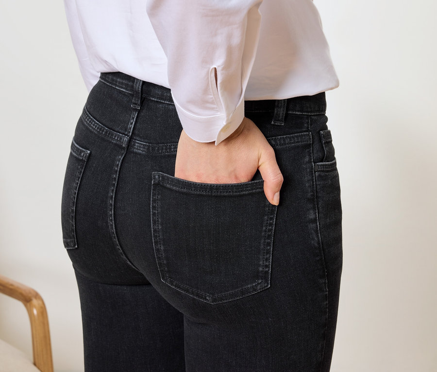 Nahaufnahme einer Frau mit der Hand in der Tasche von schwarzen Jeans und einem weißen Hemd.