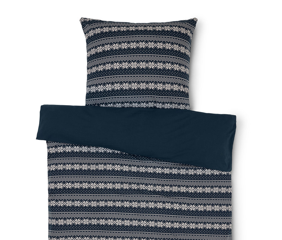 Bettwäsche mit blau-weissem Schneeflockenmuster und einfarbig blauem Bezug.
