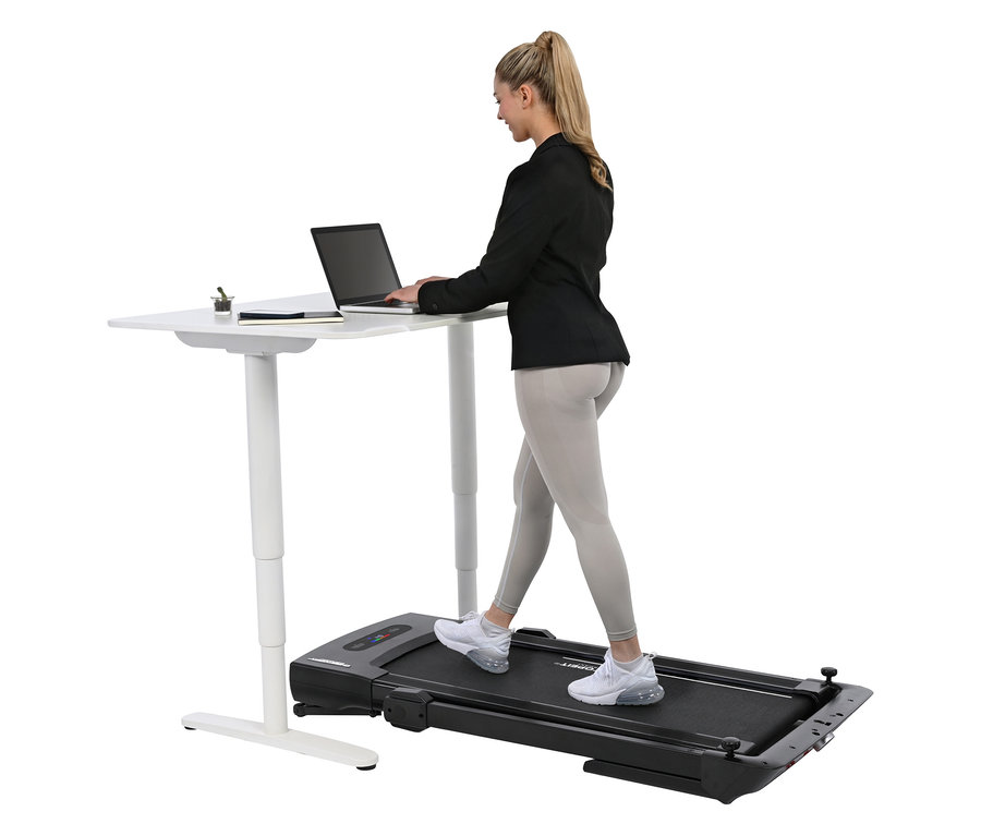 Frau geht auf einem Laufband 2 in 1 und tippt auf einem Laptop, der auf einem Stehtisch steht.
