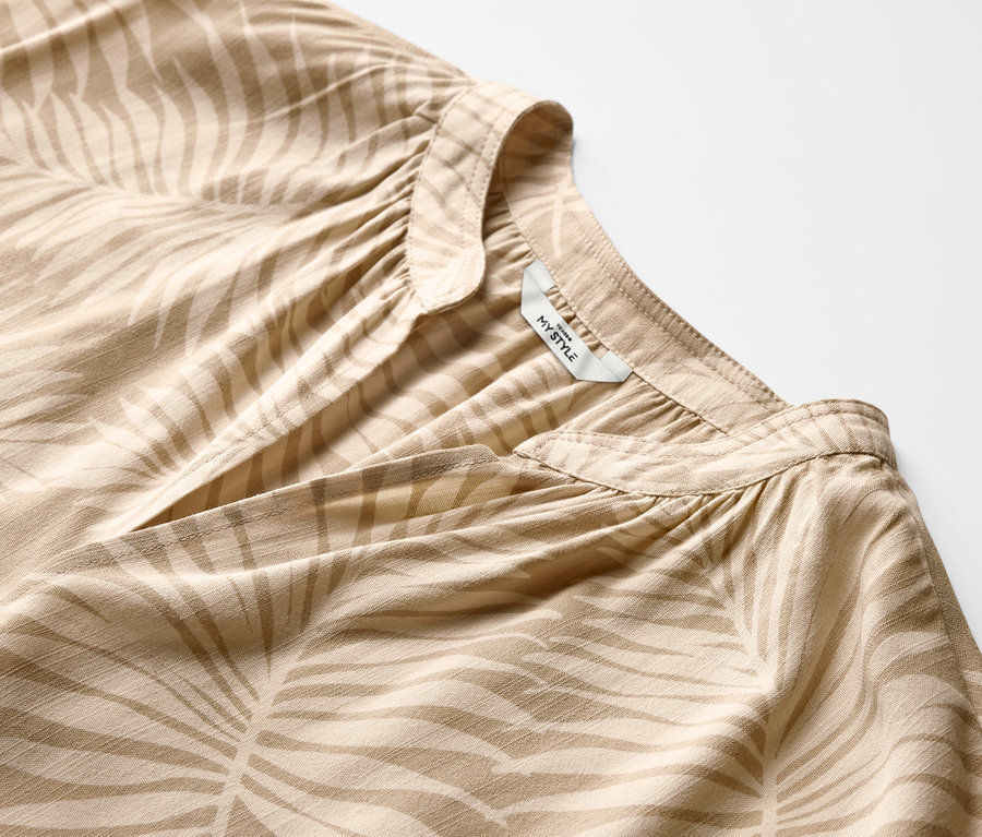 Detailansicht einer beige bedruckten Kurzarmbluse.