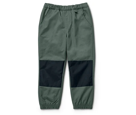 Eine grüne Hose mit schwarzen Knieflicken liegt auf einem weißen Hintergrund.