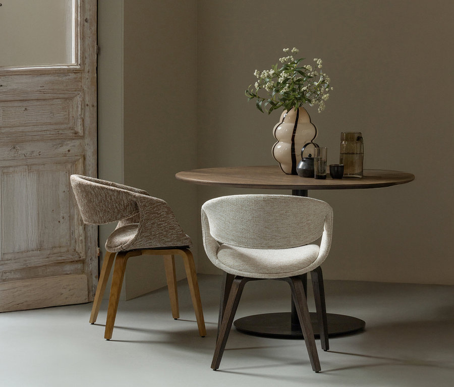 Zwei »Yossi« Esszimmerstühle mit naturfarbenem Holzfuß im 2er-Set in Sand stehen an einem runden Tisch.