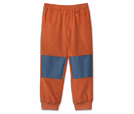 Orangefarbene Cordhose mit blauen Kniepatches liegt auf einem weißen Hintergrund.