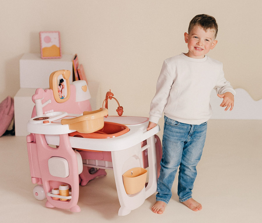 Ein Junge steht neben einem Smoby Baby Nurse Puppen-Spielcenter.