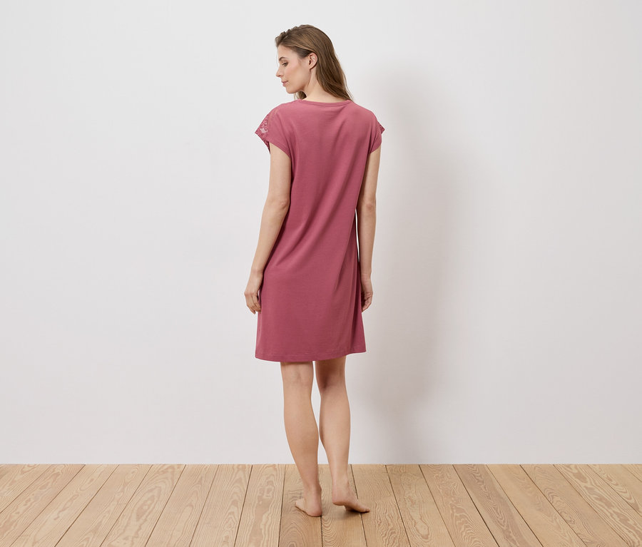 Eine Frau steht mit dem Rücken zur Kamera und trägt ein rosa Kleid.