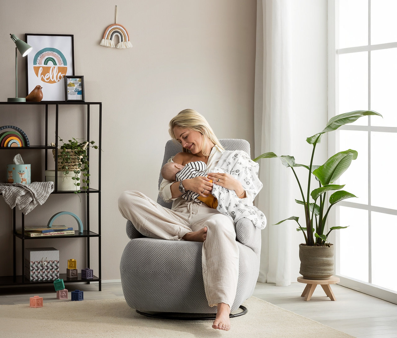 Frau stillt Baby im grauen Domo Drehsessel »Valencia« mit Drehfunktion.