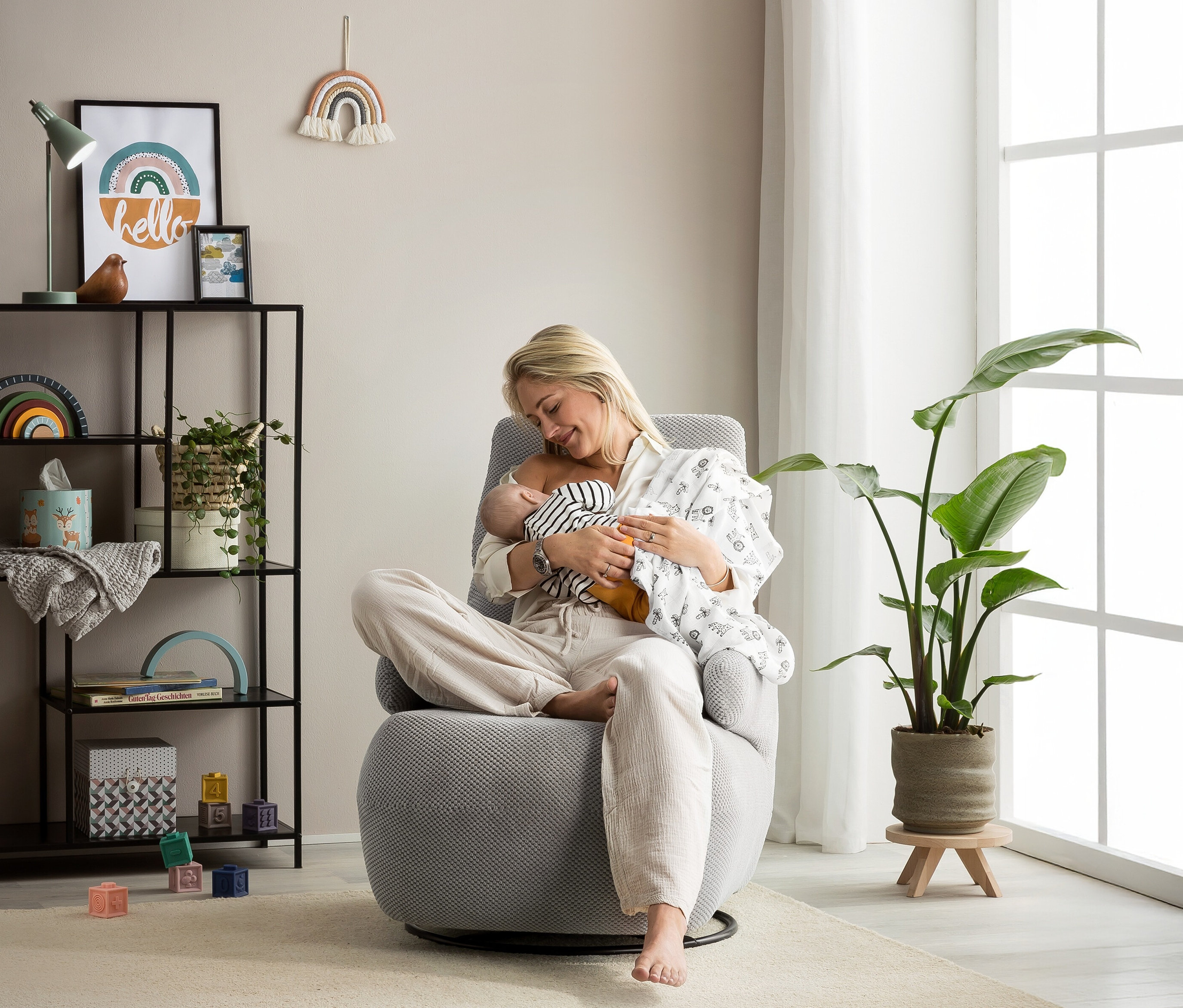 Frau stillt Baby im grauen Domo Drehsessel »Valencia« mit Drehfunktion.