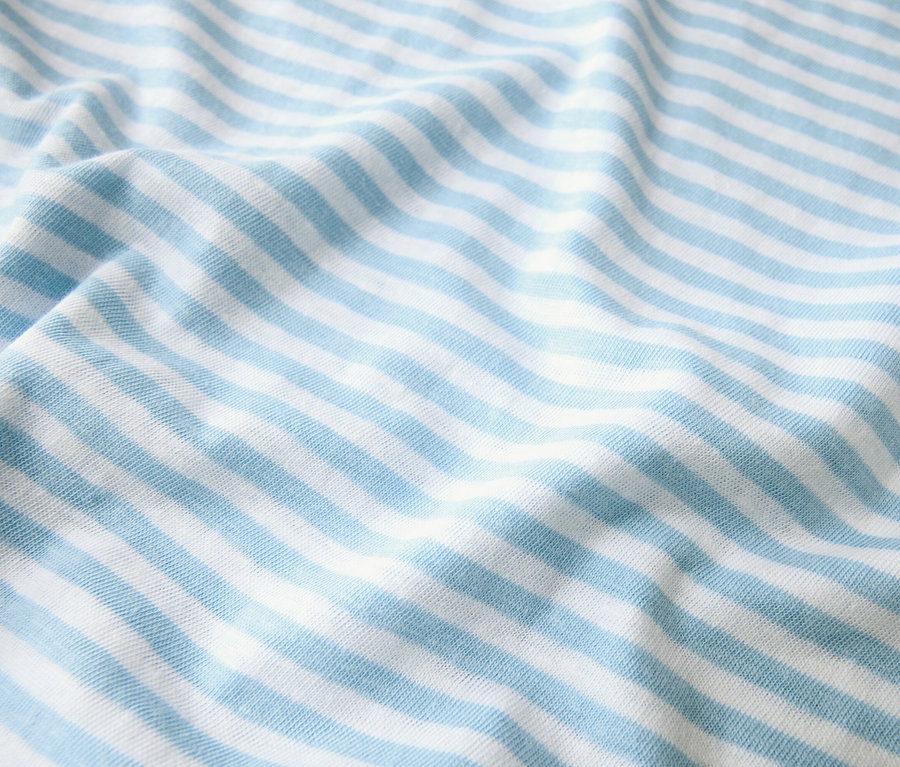 Nahaufnahme eines Stoffes mit hellblauen und weißen Streifen, der in Falten liegt.