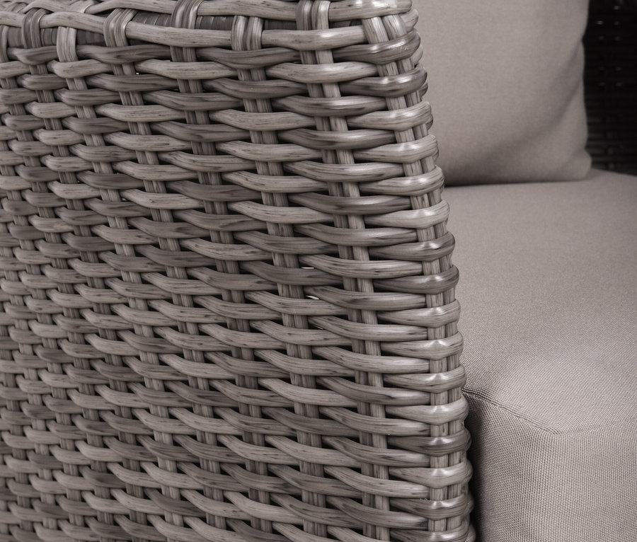 Nahaufnahme eines grauen Korbsessels mit Kissen und Armlehne.