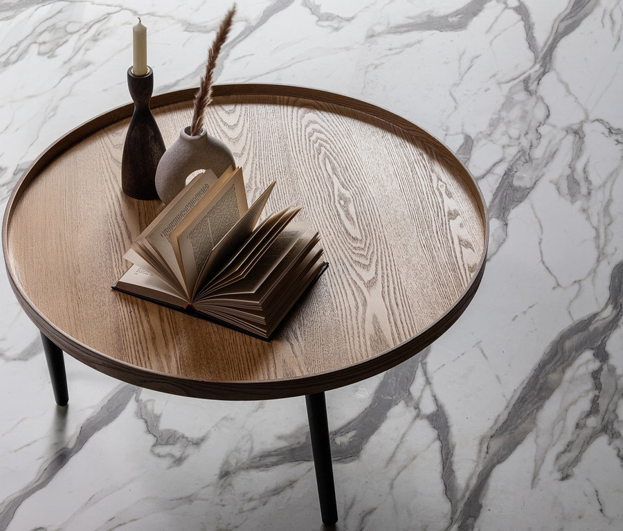 Ein naturfarbener WOOOD Beistelltisch »Mesa XL« aus Holz mit Buch, Kerzenständer und Vase auf marmoriertem Untergrund.