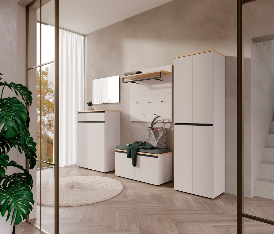 Eingangsbereich mit weißer Schuhbank »Cormano«, Garderobe, Spiegel und Pflanze auf rundem Teppich vor einer Glastür.