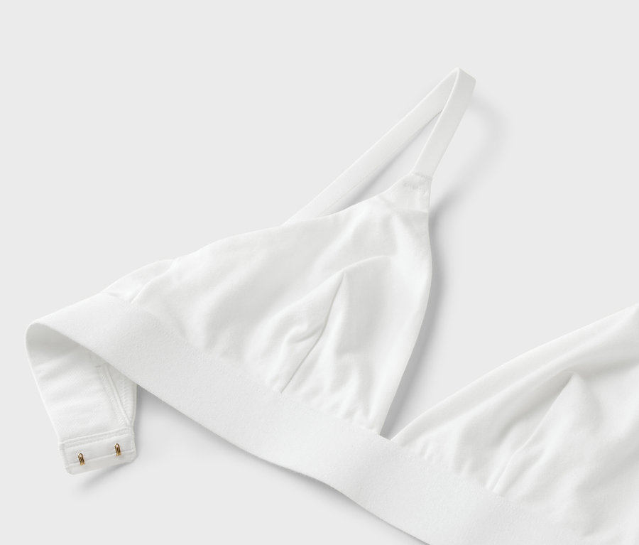 Nahaufnahme eines weißen BHs mit dünnen Trägern auf weißem Hintergrund.