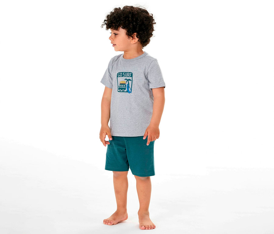 Junge steht barfuß im kurzen SCHIESSER Kinder-Pyjama mit Surf-Motiv.