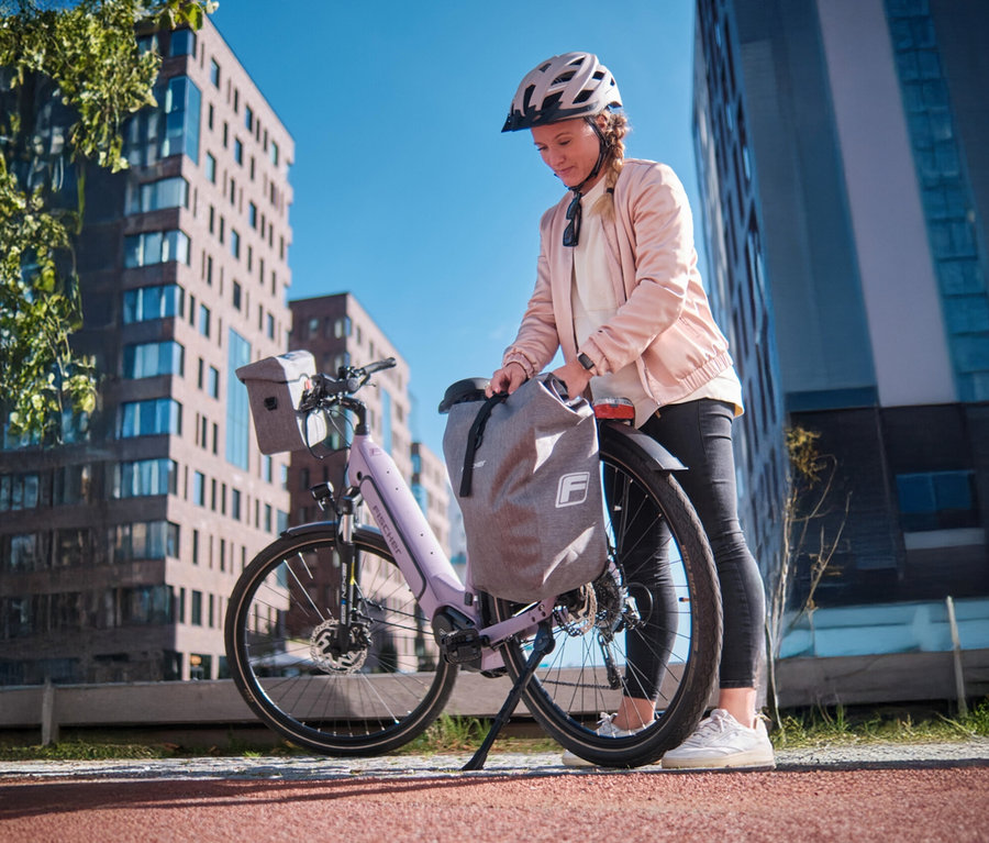 Frau befestigt Fischer Gepäckträgertasche PLUS Cita an einem Fahrrad.