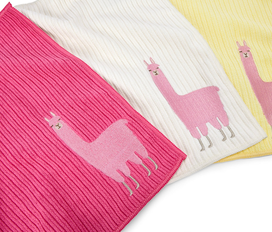 Drei Waschlappen in Pink, Weiß und Gelb liegen nebeneinander, jeder mit einem aufgestickten rosa Lama.