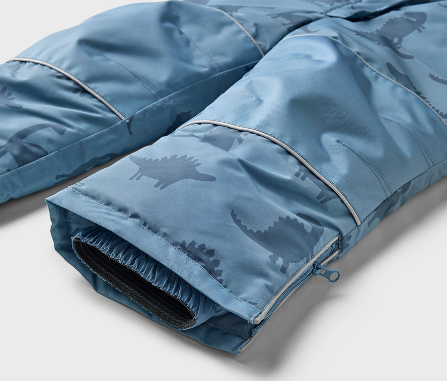 Nahaufnahme der Unterseite einer blauen Hose mit Dinosaurier-Muster und Reißverschluss am Bein.
