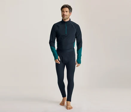 Barfüßiger Mann in dunkelblauem Langarmshirt mit türkisen Akzenten und passenden Leggings, der nach links blickt.