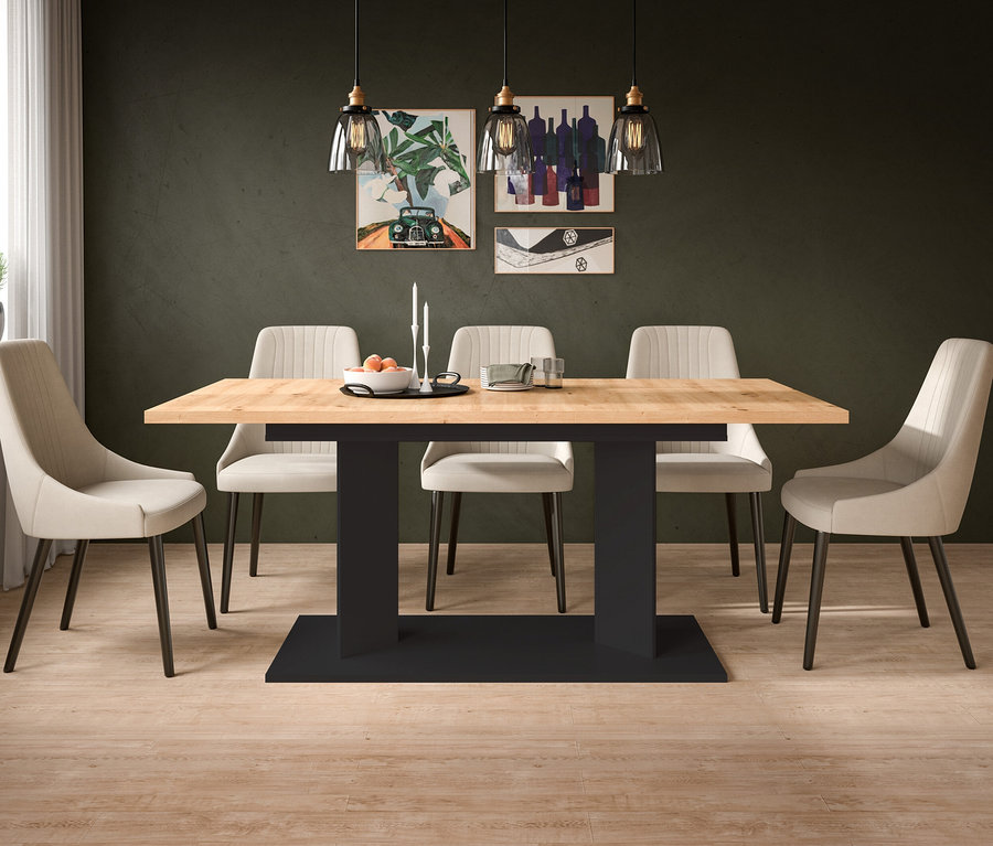 Ein modernes Esszimmer mit einem hellen Holztisch und sechs beigefarbenen Polsterstühlen. Auf dem Tisch stehen eine Schale mit Orangen, Kerzen und Servietten. Die dunkelgrüne Wand zeigt vier gerahmte Bilder und drei Pendelleuchten. Links befindet sich ein Fenster mit einer Pflanze.