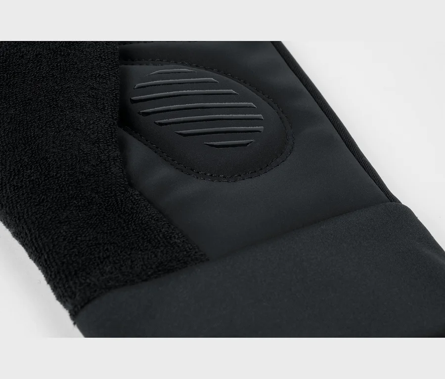 Schwarzer Handschuh mit Frottee-Bereich, glattem Stoff und einem erhabenen ovalen Gummi-Patch mit horizontalen Rillen.