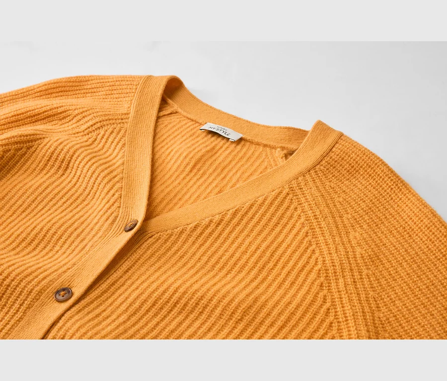 Senfgelbe gerippte Strickjacke mit V-Ausschnitt und zwei braunen Knöpfen. Ein weißes 'MYSTYLE'-Etikett ist im Nacken sichtbar.