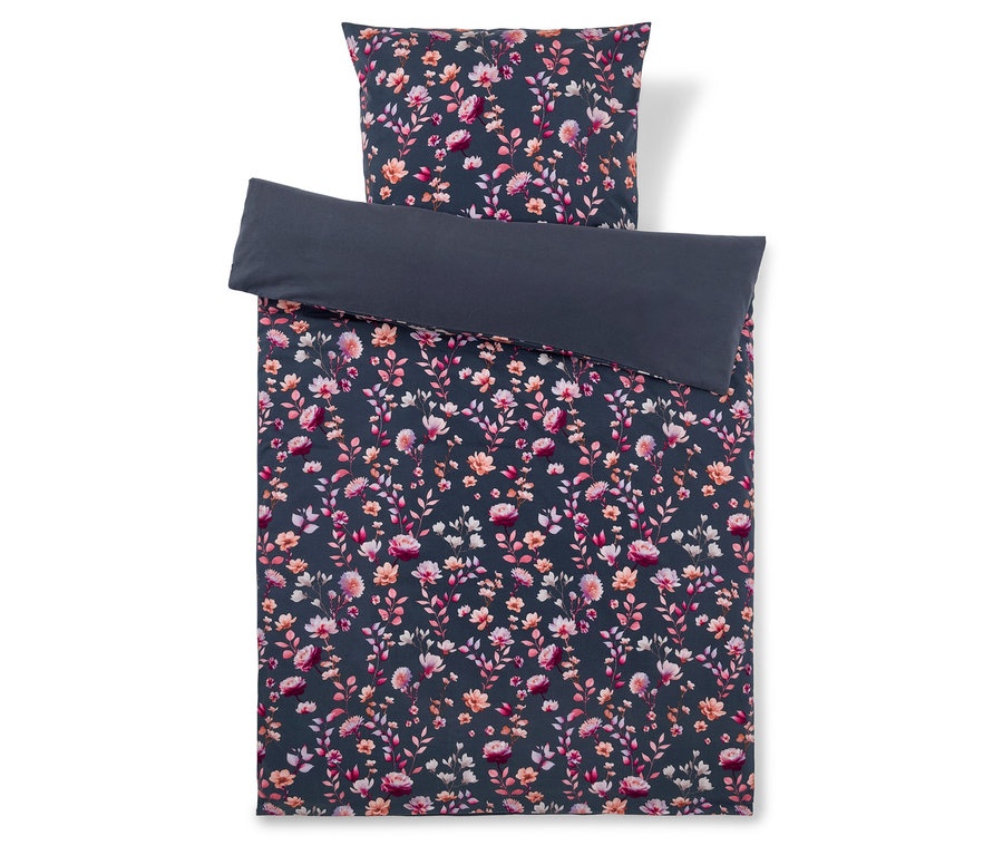 Dunkelgrauer Bettbezug mit einem Muster aus rosa, orangefarbenen und weißen Blüten und Blättern, dazu ein passender floraler Kissenbezug und ein einfarbiger dunkelgrauer Kissenbezug, der darauf gefaltet liegt.