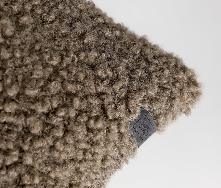 Nahaufnahme eines taupefarbenen, flauschigen SCHÖNER WOHNEN-Kollektion Dekokissenbezugs »TEDDY« mit kleinem Etikett.
