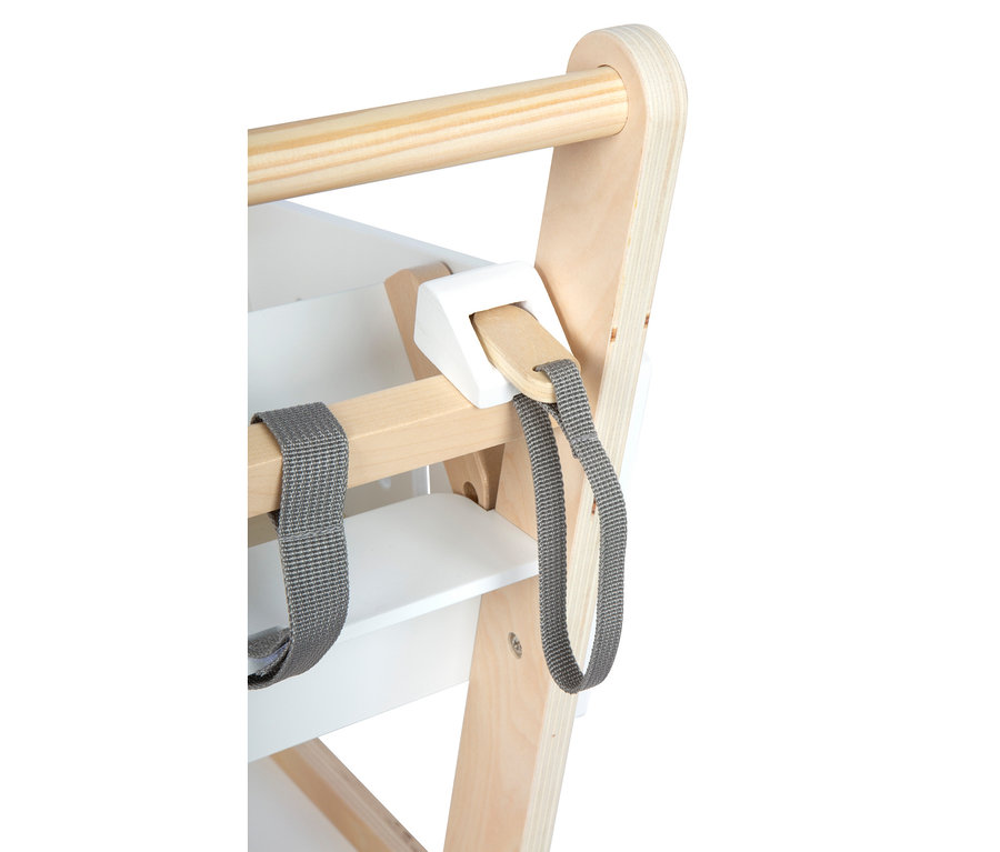 Nahaufnahme eines Holzhochstuhls mit naturfarbenen und weiß lackierten Holzteilen. Eine horizontale Holzstange ist oben, und graue Stoffgurte hängen von einer unteren Holzstange, die von einem weißen Block gehalten wird.