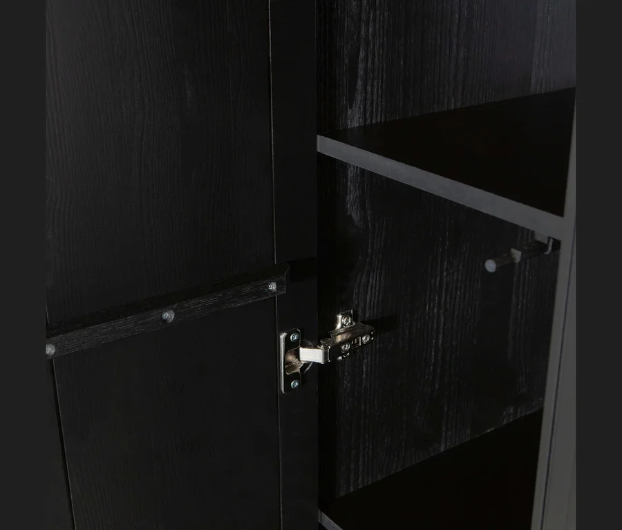 Nahaufnahme einer offenen dunklen Holzschranktür mit Metallscharnier, die dunkle Regalböden und einen weißen Stift im Inneren zeigt.