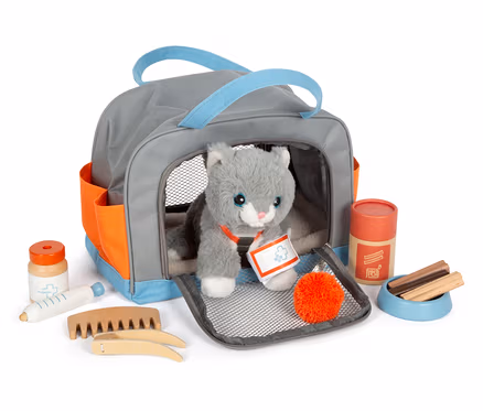 Graue small foot Tasche mit Plüschkatze und Pflege-Set. Die Katze sitzt in der Tasche, um sie herum liegen Pflegeutensilien.
