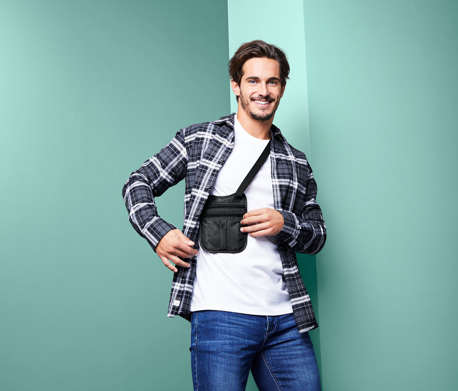 Lächelnder Mann trägt eine schwarze Sicherheitstasche mit Schultergurt quer über dem Körper.