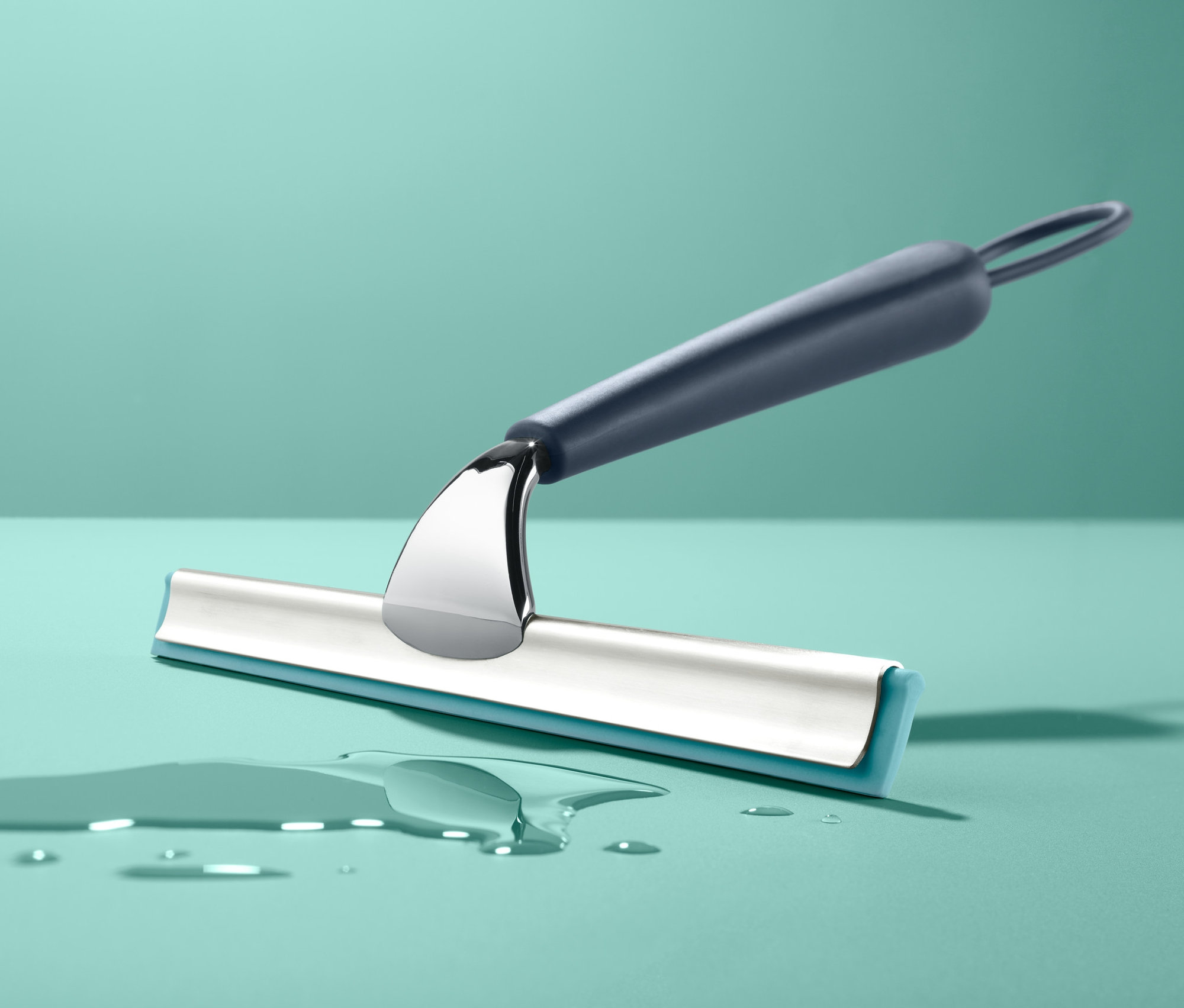 Ein Badwischer liegt auf einer blaugrünen Oberfläche neben Wassertropfen.