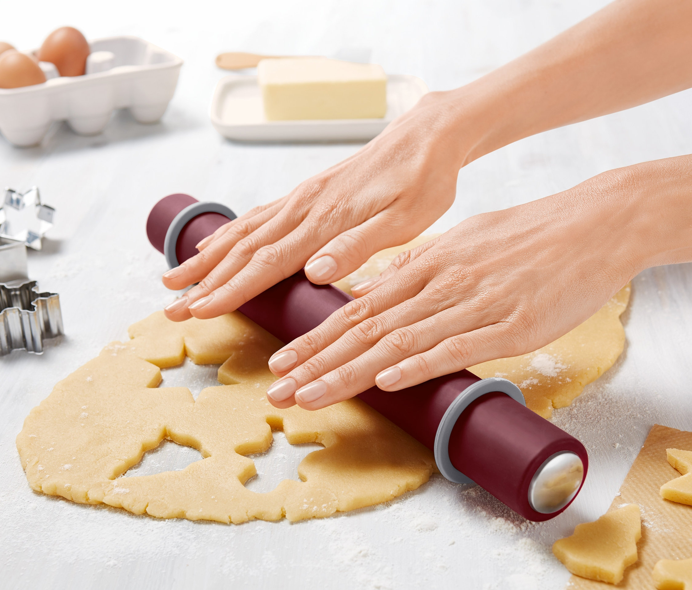 Frau rollt Teig mit einer Teigrolle aus.