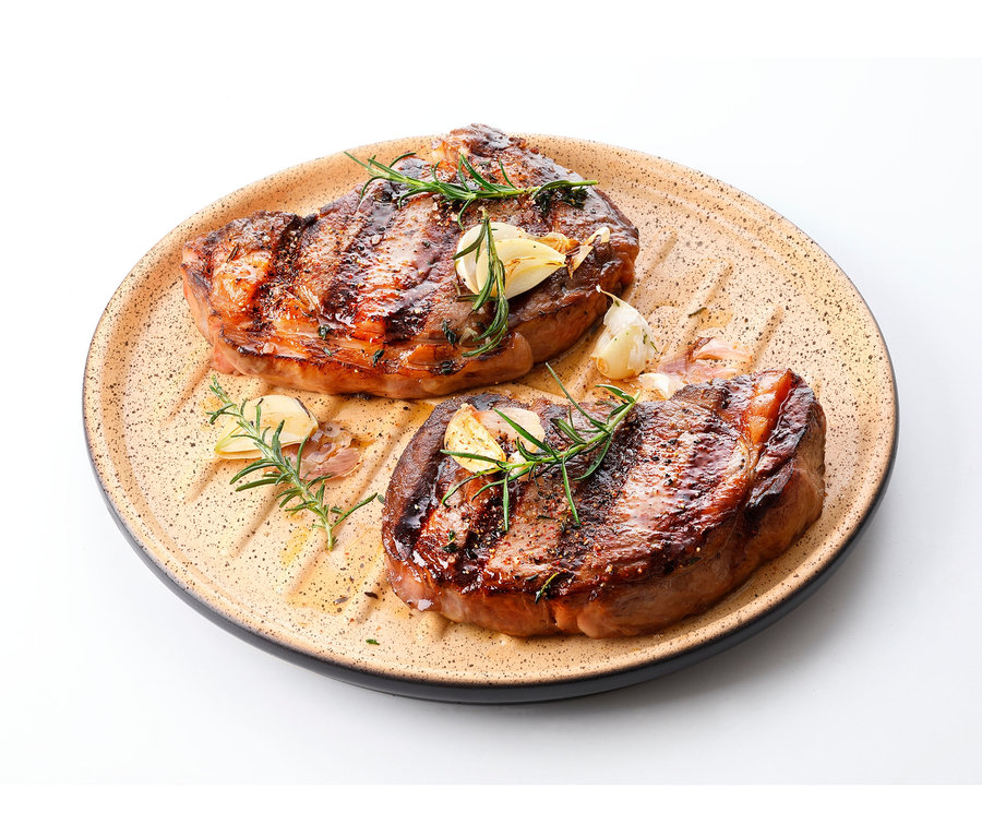 Zwei Steaks mit Knoblauch und Rosmarin auf Römertopf »Lafer Plancha«.