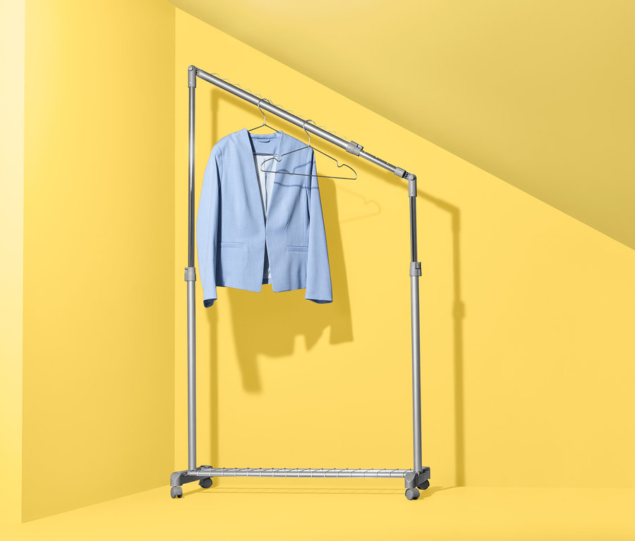 Ein hellblauer Blazer hängt auf einem höhenverstellbaren Kleiderständer.