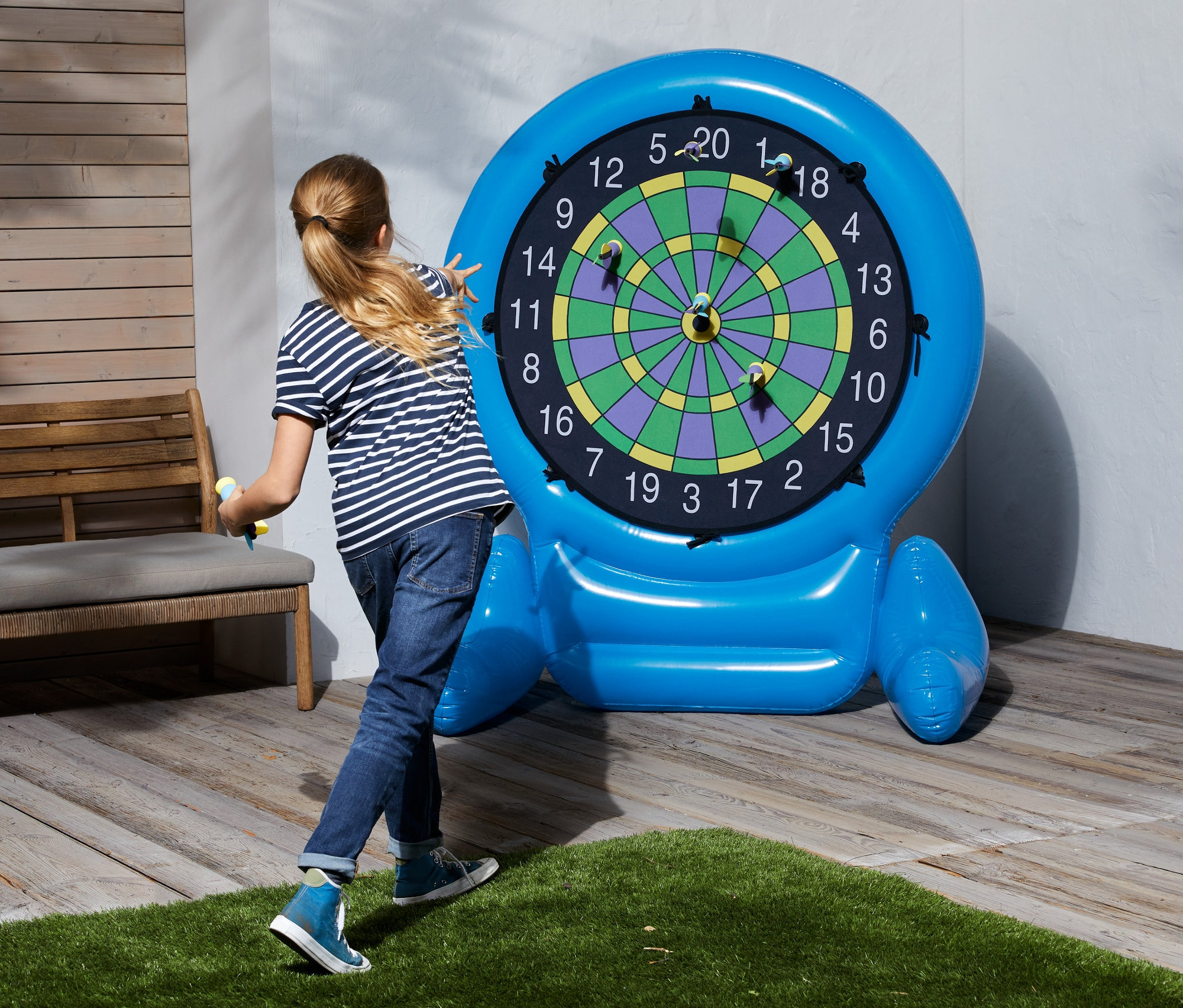 Mädchen wirft Pfeile auf aufblasbares XL-Dartspiel.