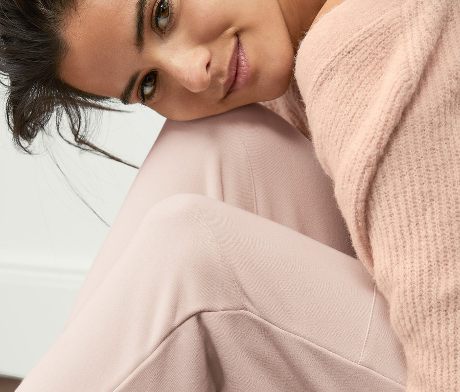 Frau sitzt mit Sweatpants und Pullover am Boden.