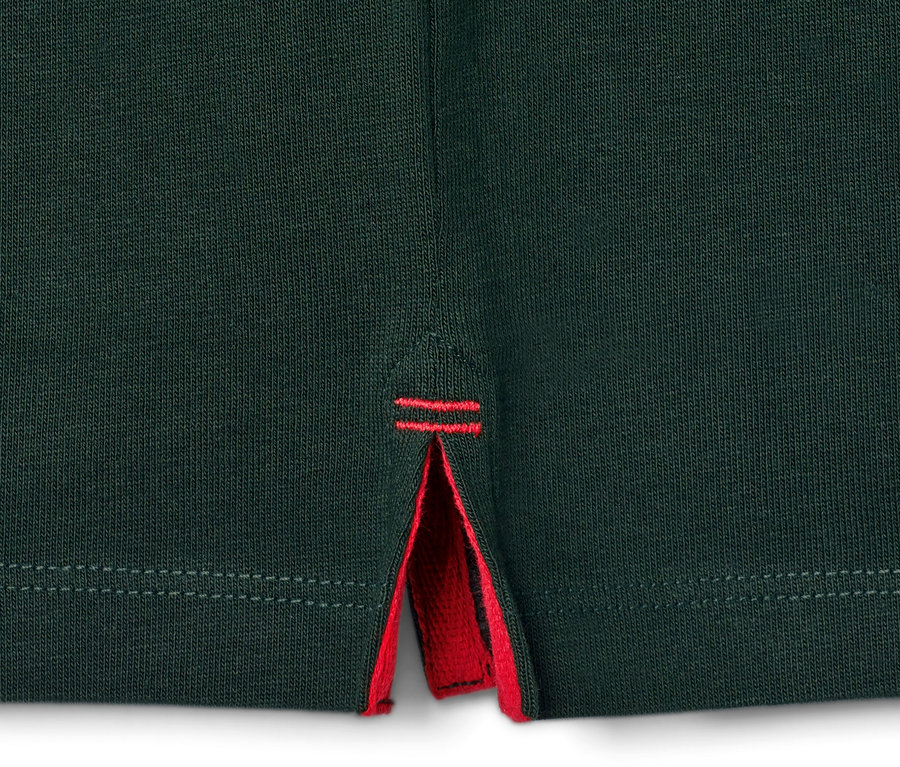 Detailaufnahme eines grünen Langarm-Poloshirts mit rotem Saum.