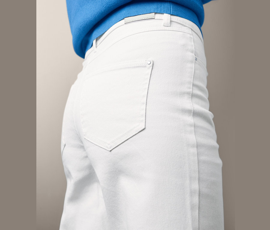 Detail einer Frau, die Culotte-Jeans und einen blauen Pullover trägt.