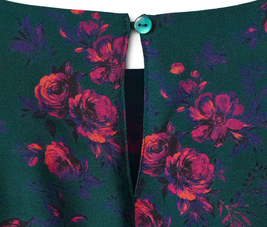 Detail eines Viskosekleids mit grünem Hintergrund und rot-violetten Blumen.