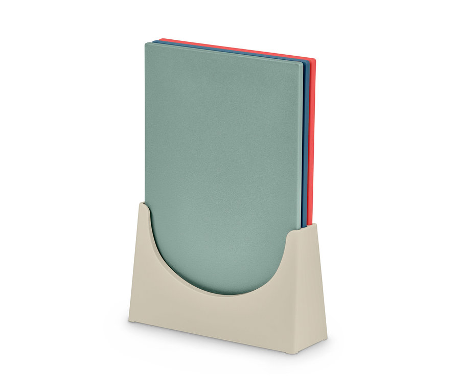 Ein Set aus drei Schneidebrettern in einem beigen Halter. Die Bretter sind grün, blau und rot.