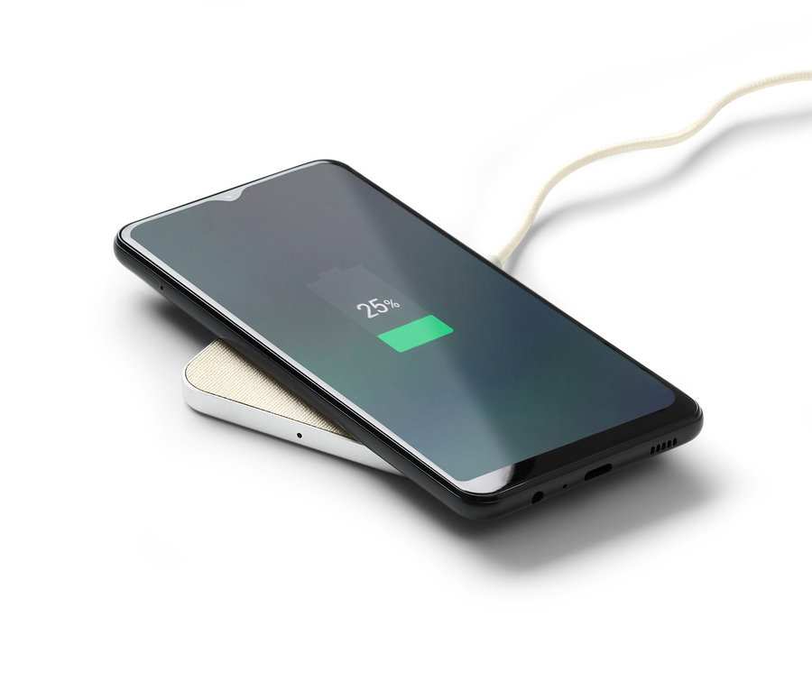 Ein graues, kabelloses Ladegerät lädt ein schwarzes Smartphone auf, der Telefonbildschirm zeigt 25 %.