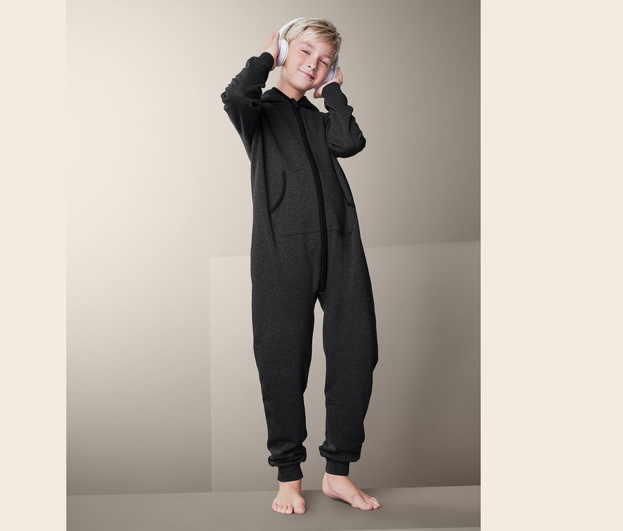 Ein blonder Junge mit Kopfhörern trägt einen grauen Sweat-Loungeoverall.