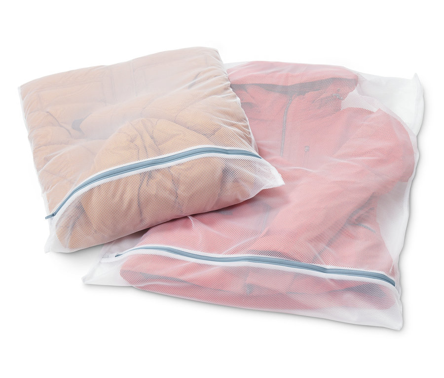 Zwei weiße XL-Wäschenetze, gefüllt mit Kleidung, liegen auf einem weißen Hintergrund.