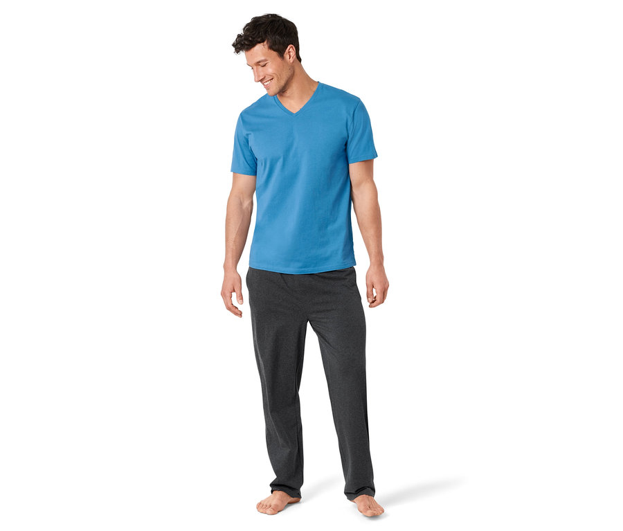 Mann trägt ein blaues T-Shirt und eine graue Pyjamahose aus einem 3-teiligen Pyjama-Set.