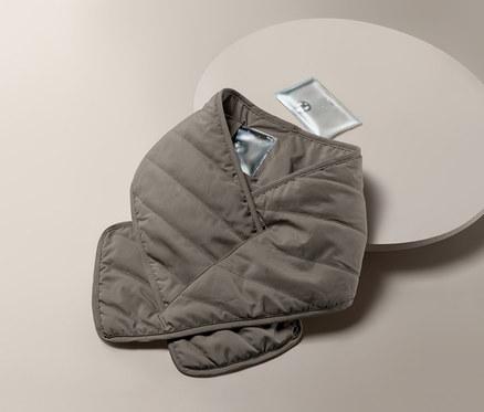 Ein Stepp-Schal mit Heizkissen liegt auf einem runden Tisch.