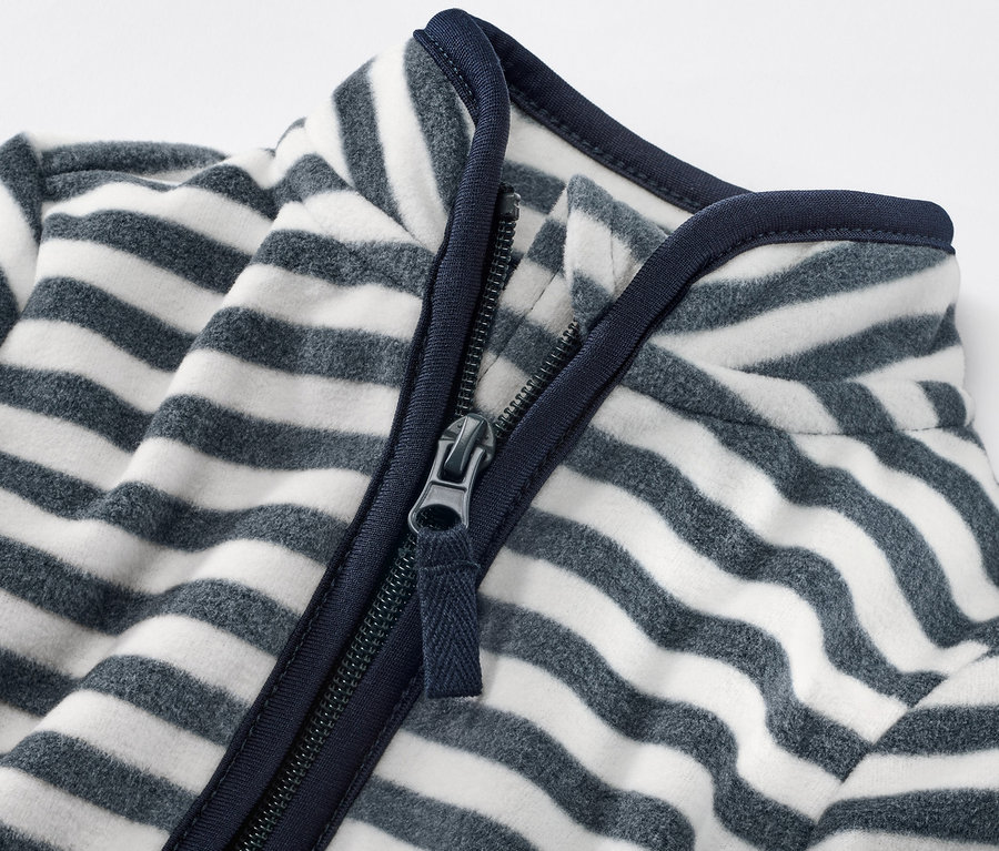 Detailansicht einer Kinder-Fleecejacke mit Ringeln und Reißverschluss.