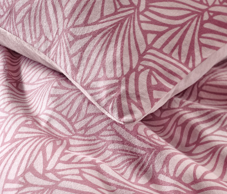 Nahaufnahme von Kissen und Bettdecke mit geometrischem Blumenmuster. Es handelt sich um Winterjersey-Bettwäsche.