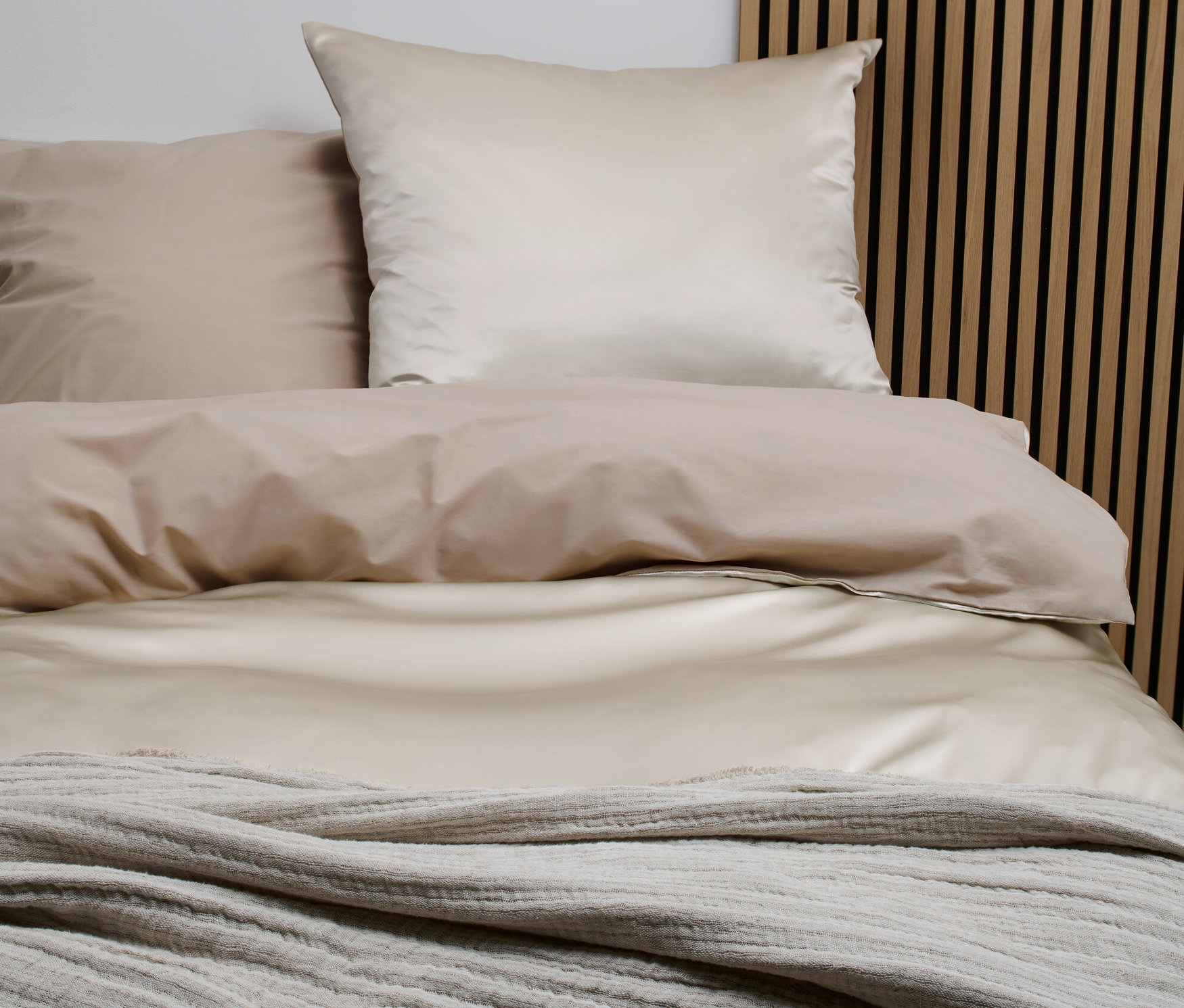 Seiden-Baumwoll-Bettwäsche in Normalgröße liegt auf einem Bett mit hölzernem Kopfteil.